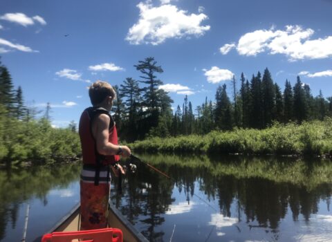 kid standing on kayak on river